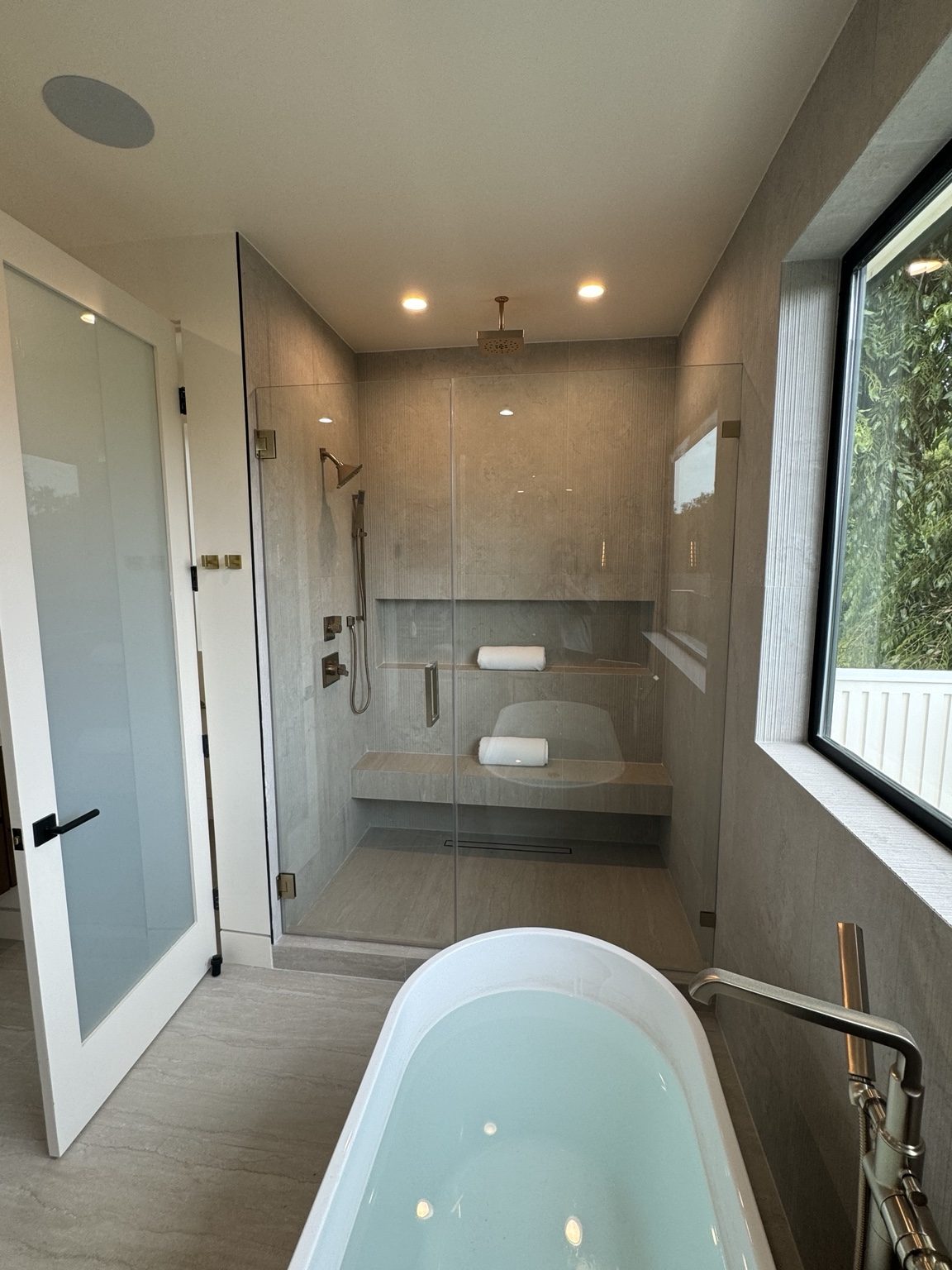 Modern primary bathroom with soaking tub and glass shower by Coastline DC