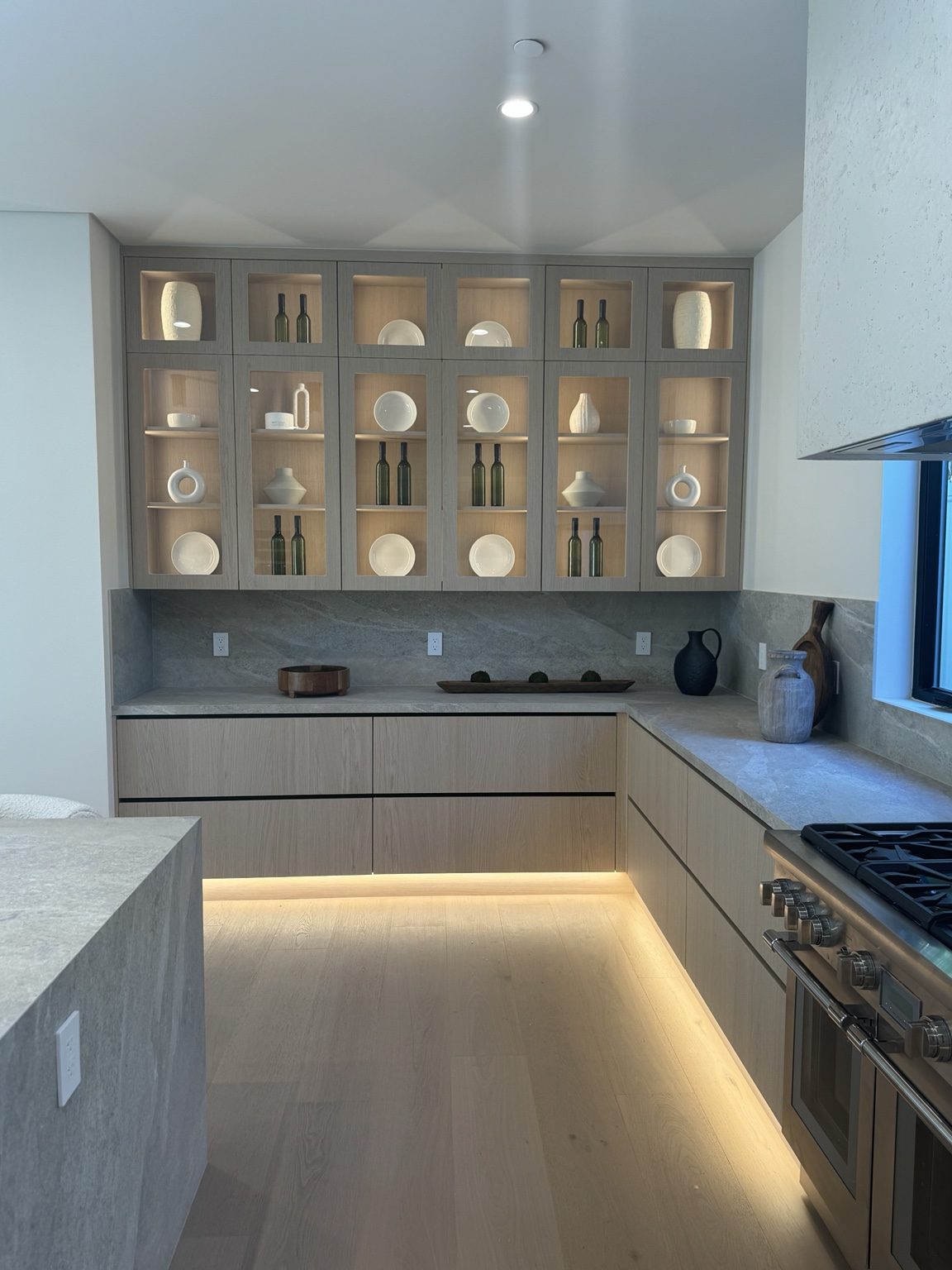 Glass-front kitchen cabinetry with interior lighting by Coastline DC
